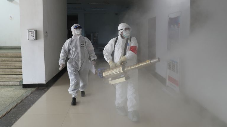 Volunteers in protective suits disinfect a residential compound in Wuhan