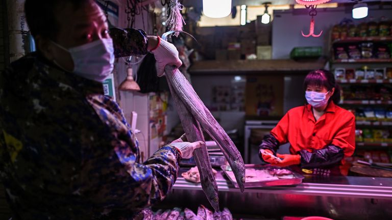 A man wearing a face mask holds a fish in a market in Wuhan, in China&#39;s central Hubei province on April 7, 2020. - Wuhan, the central Chinese city where the coronavirus first emerged last year, partly reopened on March 28 after more than two months of near total isolation for its population of 11 million. (Photo by Hector RETAMAL / AFP) (Photo by HECTOR RETAMAL/AFP via Getty Images)
