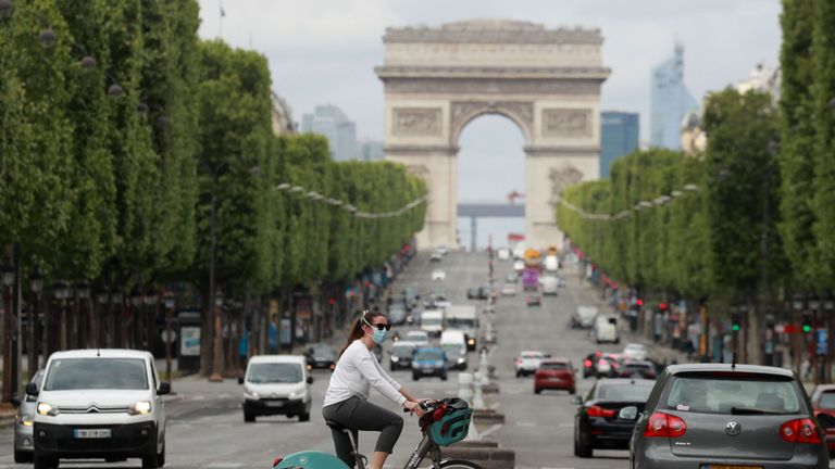 A cyclist wears a facemask as she crosses The Champs Elysees Avenue in Paris on May 4, 2020, on the forty-ninth day of a strict lockdown in France, in place to attempt to stop the spread of the new coronavirus (COVID-19). (Photo by Ludovic MARIN / AFP) (Photo by LUDOVIC MARIN/AFP via Getty Images)