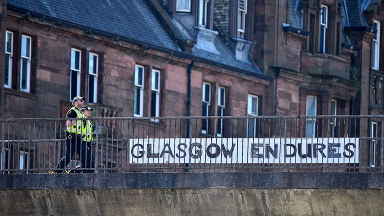 GLASGOW, SCOTLAND - MAY 06: Two police officers walk past a sign at Charing Cross during the coronavirus lockdown on May 6, 2020 in Glasgow, Scotland.  The country continues quarantine measures intended to curb the spread of Covid-19, but the infection rate is falling, and government officials are discussing the terms under which it would ease the lockdown. (Photo by Jeff J Mitchell/Getty Images)