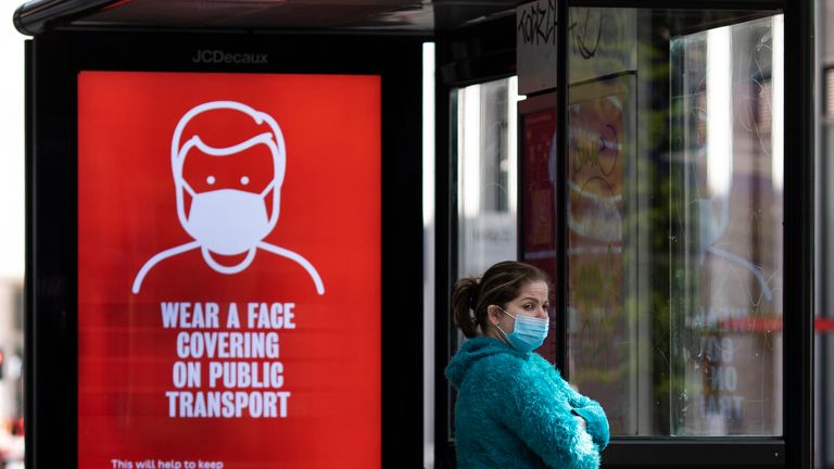 LONDON, ENGLAND  - MAY 18: A woman wearing a face mask stands at a bus stop next to a sign about wearing face masks on public transport on May 18, 2020 in London, England. The British government has started easing the lockdown it imposed two months ago to curb the spread of Covid-19, abandoning its 'stay at home' slogan in favour of a message to 'be alert', but UK countries have varied in their approaches to relaxing quarantine measures. (Photo by Dan Kitwood/Getty Images)