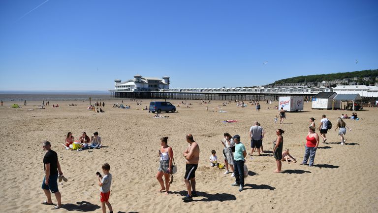 Sunbathers social distancing as they queue for ice cream as they enjoy the hot weather at Weston-super-Mare, as people flock to parks and beaches with lockdown measures eased.