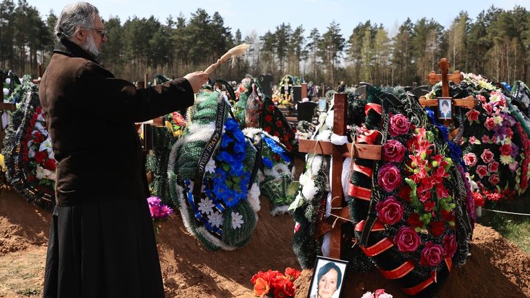 A priest blesses a new grave where a Belarusian COVID-19 victim has been recently buried. Pic: Irina Alekhovskaya/Belsat