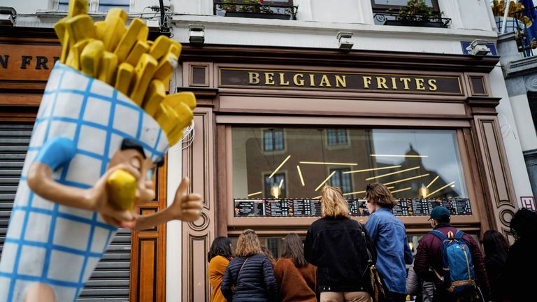People stand in line in front of a French fries vendor near the Grand Place in central Brussels