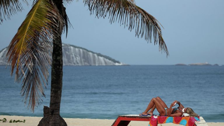 A woman wearing a protective face mask sunbaths in Ipanema beach amid the coronavirus outbreak in Rio de Janeiro