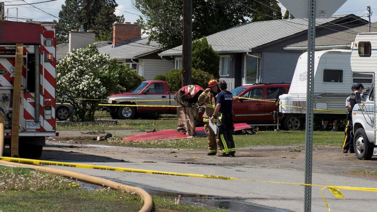 Fire officials talk in a residential neighbourhood street in front of the tail wreckage from a Royal Canadian Air Force Snowbirds jet after a member of the exhibition team crashed shortly after takeoff in Kamloops, British Columbia, Canada May 17, 2020. REUTERS/Dennis Owen