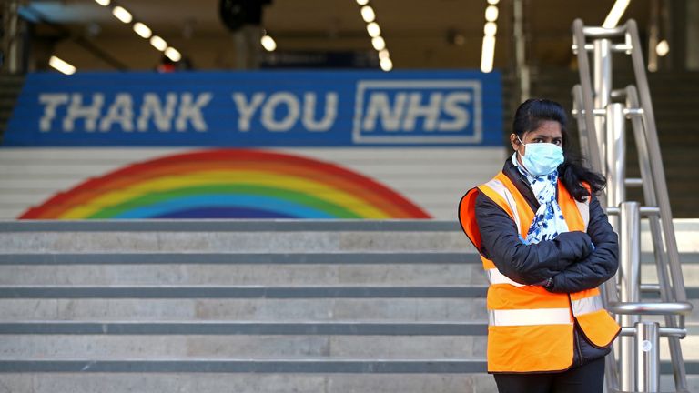 A worker wearing PPE (personal protective equipment), including a face mask as a precautionary measure against COVID-19, stands at the entrance to Cannon Street national rail station in central London on May 14, 2020