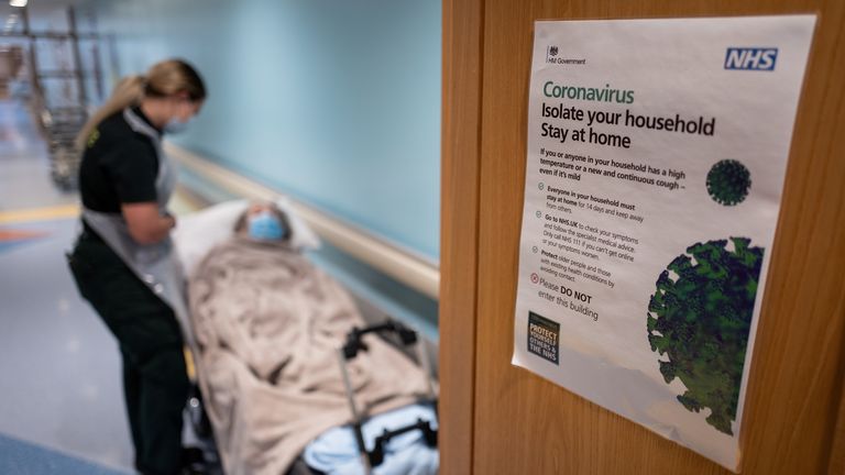 An NHS worker speaks to an elderly patient as she is moved from hospital to a care home