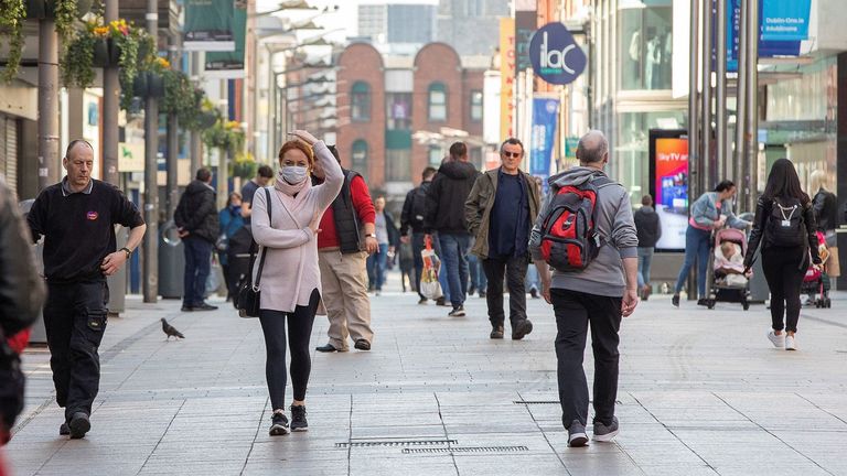 Some people wear face masks as they walk past shops in Dublin