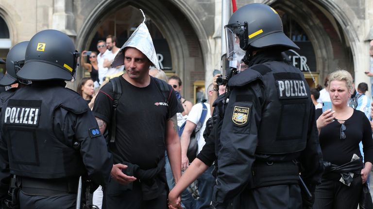 Police officers talk to a protester against coronavirus restrictions in Munich