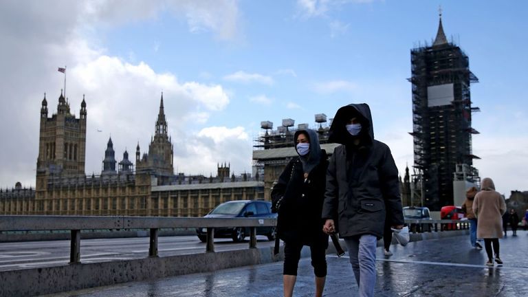 Pedestrian wearing a face mask walks along Westminster Bridge in front of the Houses of Parliament in London on March 12, 2020. - The British government was expected Thursday to implement the second phase of its plan to deal with the coronavirus outbreak but rejected calls for parliament to be suspended after an MP tested positive. (Photo by Isabel Infantes / AFP) (Photo by ISABEL INFANTES/AFP via Getty Images)
