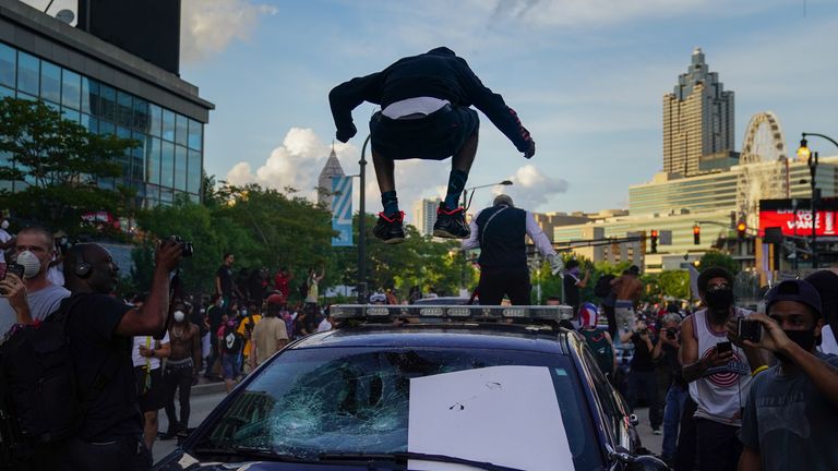 A man jumps on the roof of a police car during a protest over the Minneapolis death of George Floyd while in police custody outside CNN Center on May 29, 2020 in Atlanta, Georgia. (Photo by Elijah Nouvelage/Getty Images)