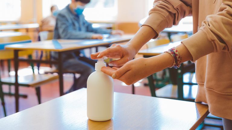 A teacher uses hand sanitiser during a socially-distanced lesson. File pic