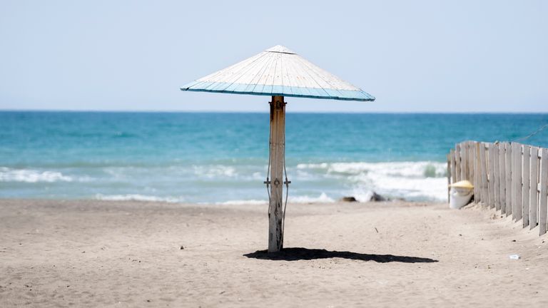 An umbrella is seen on an empty and closed beach in the seaside town of Ostia in Italy