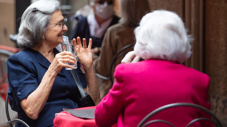 Women are seen enjoying a drink al fresco as Italy began easing lockdown on 18 March