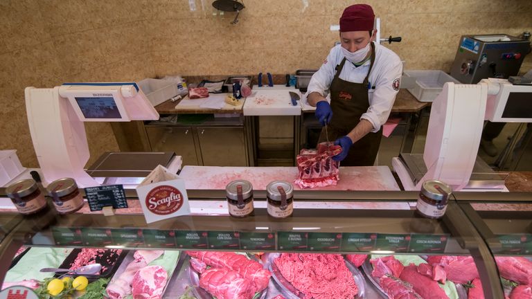 Torino yakınlarındaki Rivoli'de bir kasap iş başında.  İtalya Pazartesi gününden itibaren karantina kısıtlamalarını hafifletmeyi planlıyor