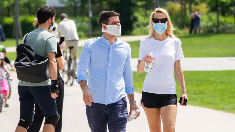 Couples stroll through a park in Milan after lockdown restriction were eased