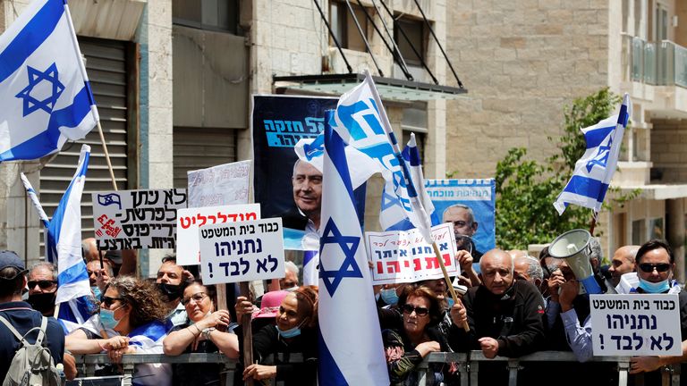 Supporters of Israeli Prime Minister Benjamin Netanyahu wave Israeli flags and hold placards as they rally just before Netanyahu&#39;s corruption trial opens, outside the District Court in Jerusalem May 24, 2020. REUTERS/Ronen Zvulun