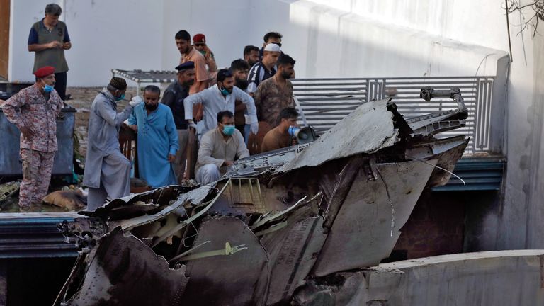 People stand next to the debris of a plane after crashed in a residential area near an airport in Karachi, Pakistan May 22, 2020. REUTERS/Akhtar Soomro