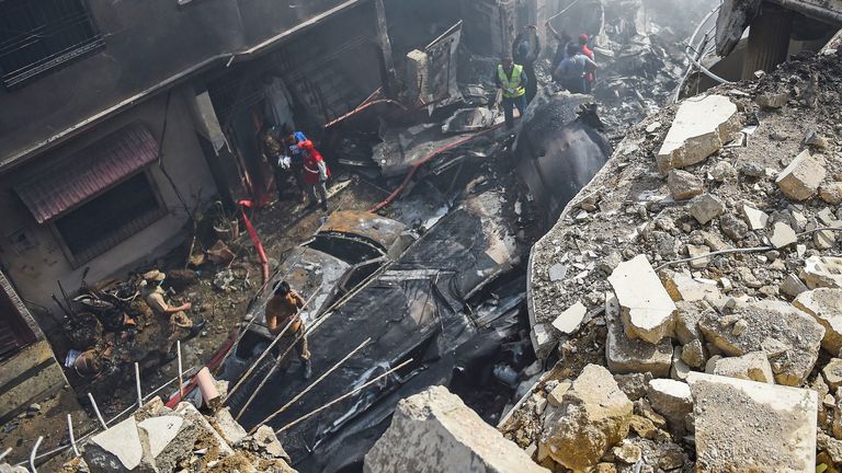 Rescue workers gather at the site after a Pakistan International Airlines aircraft crashed in a residential area in Karachi on May 22, 2020. - A Pakistani plane with nearly 100 people on board crashed into a residential area in the southern city of Karachi on May 22, killing several people on the ground. (Photo by Rizwan TABASSUM / AFP) (Photo by RIZWAN TABASSUM/AFP via Getty Images)