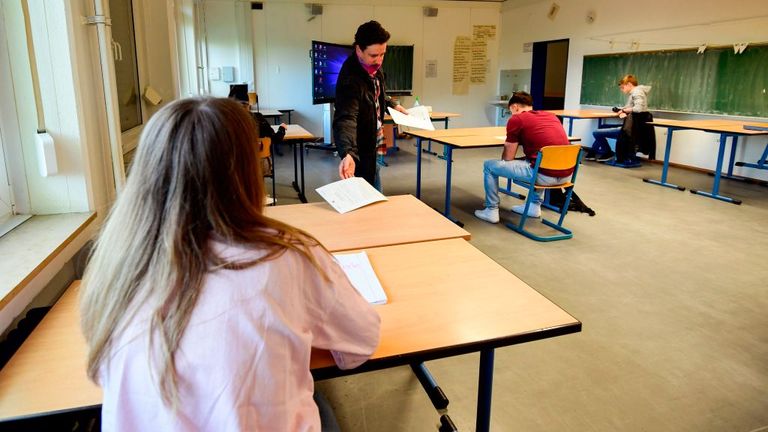 A teacher talks to few pupils who are socially distancing preparing in their school in Dortmund