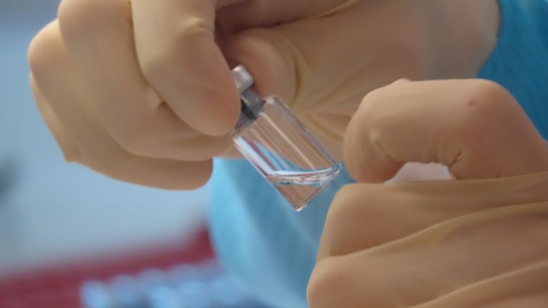 A scientist cleans vaccine vials 