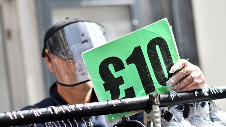 A stall holder wearing PPE (personal protective equipment), including a full face visor and gloves as a precautionary measure against COVID-19, puts out stock at his clothing stall at Petticoat Lane Market in London on June 7, 2020, as lockdown measures are partially eased during the COVID-19 pandemic. - Outdoor markets swung open their gates on June 1, and car showrooms tried to lure back customers and recoup losses suffered since Britain effectively shut down for business on March 23, to ward off a disease that has now officially claimed more than 40,000 lives in the country. Britain's Health Ministry said 40,261 people who tested positive for COVID-19 had died as of 0800 GMT on Friday June 5. (Photo by JUSTIN TALLIS / AFP) (Photo by JUSTIN TALLIS/AFP via Getty Images)