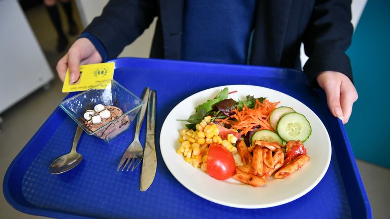 A student carries their school dinner on a tray and their lunch pass during lunch in the canteen at Royal High School Bath, which is a day and boarding school for girls aged 3-18 and also part of The Girls' Day School Trust, the leading network of independent girls' schools in the UK.