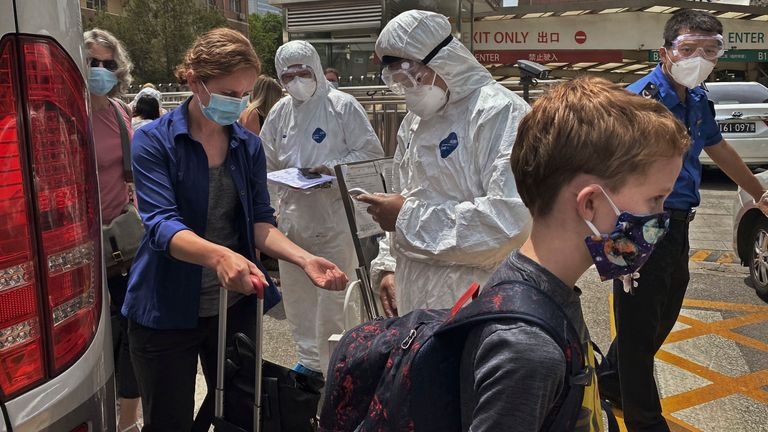 Officials in protective suits and masks carry out temperature checks and register people arriving in Beijing, China