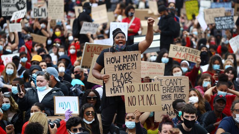 People wearing face masks hold banners in Hyde Park during a "Black Lives Matter" protest following the death of George Floyd who died in police custody in Minneapolis, London, Britain, June 3, 2020. REUTERS/Hannah McKay