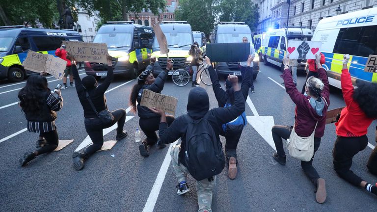 Protesters take a knee in front of police vans in Parliament Square,