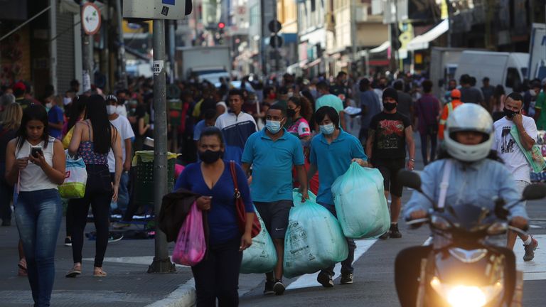 People walk with bags at a popular shopping street amid the coronavirus disease (COVID-19) outbreak, in Sao Paulo, Brazil