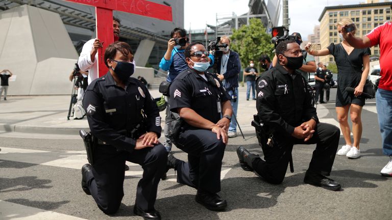 Police officers kneel during a protest against the death in Minneapolis police custody of George Floyd, outside LAPD headquarters in Los Angeles, California, U.S. June 2, 2020. REUTERS/Lucy Nicholson