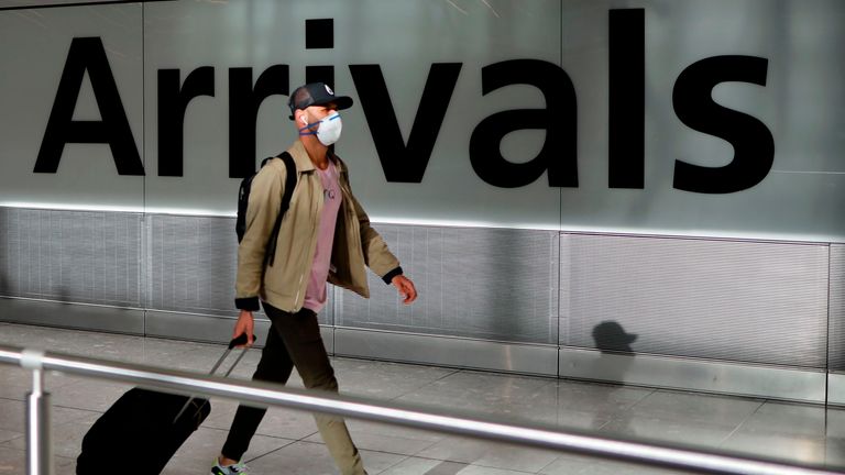 A passenger wearing a face mask as a precaution against the novel coronavirus arrive at Heathrow airport, west London, on May 22, 2020