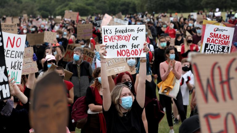 Protesters wearing face masks hold up signs during a Black Lives Matter protest in Hyde Park 