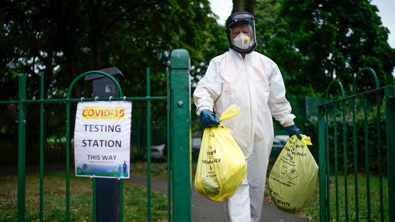 A city council worker is seen carrying rubbish from a coronavirus testing centre in Leicester 