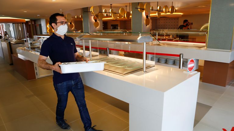 A worker wearing a protective face mask prepares the buffet area in a hotel at Playa De Palma beach