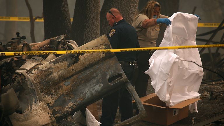 Police officers prepare to remove human remains that were found in a car in Paradise