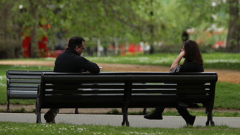 People observing social distancing on a bench in Hyde Park, London