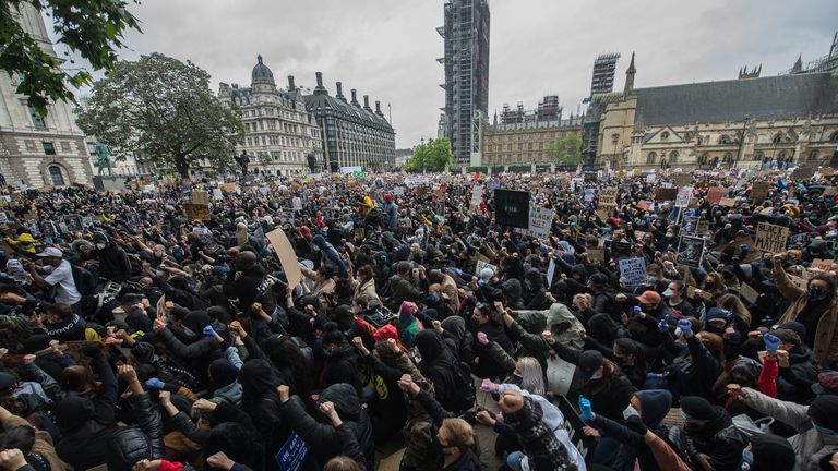 Protesters raise their fists in the air as they gather in Parliament Square for a rally as thousands of people join a Black Lives Matter protest 
