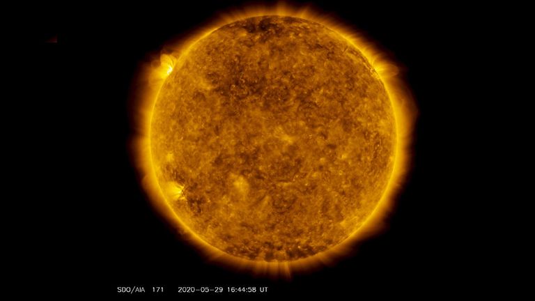 On the upper left side of this image from May 29, 2020, from NASA&#39;s Solar Dynamics Observatory — shown here in the 171-angstrom wavelength, which is typically colorized in gold — one can see a spot of light hovering above the left horizon. This light emanates from solar material tracing out magnetic field lines that are hovering over a set of sunspots about to rotate over the left limb of the Sun. Credit: NASA/Solar Dynamics Observatory/Joy Ng