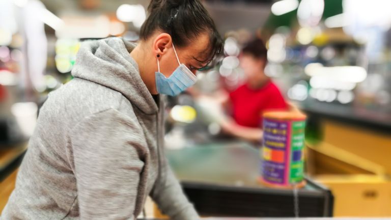 Woman wearing protective face mask and gloves at checkout