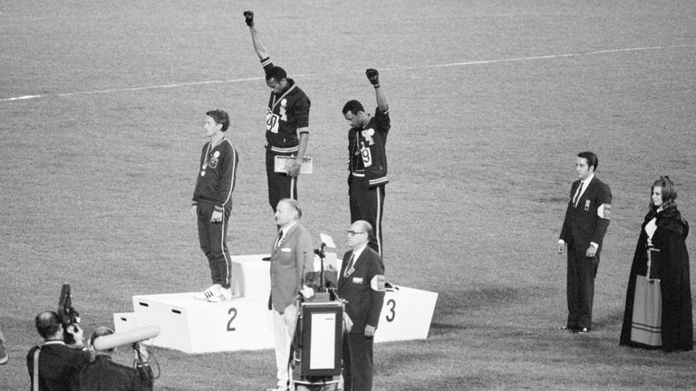 Tommie Smith and John Carlos, gold and bronze medalists in the 200-meter run at the 1968 Olympic Games, engage in a victory stand protest against unfair treatment of blacks in the United States. With heads lowered and black-gloved fists raised in the black power salute, they refuse to recognize the American flag and national anthem. Australian Peter Norman is the silver medalist.