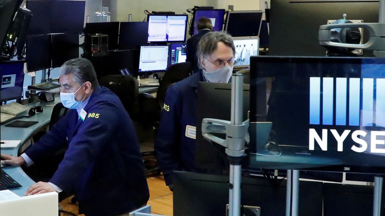 FILE PHOTO: Traders wear masks as they work on the floor of the New York Stock Exchange as the outbreak of the coronavirus disease (COVID19) continues in the Manhattan borough of New York, U.S., May 27, 2020