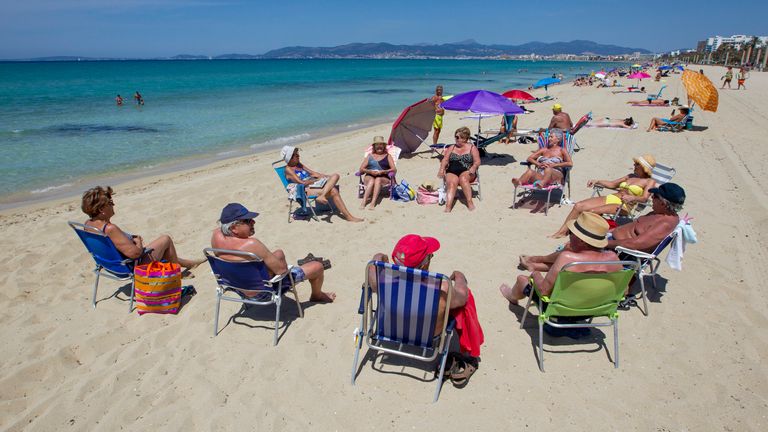 People sunbathe at Palma Beach in Palma de Mallorca 