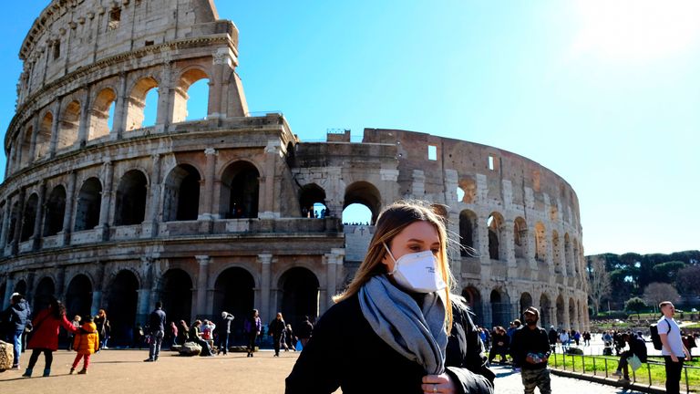 Tourist wearing a protective respiratory mask tours outside the Colosseo monument (Colisee, Coliseum) in downtown Rome on February 28, 2020 amid fear of Covid-19 epidemic. - Since February 23, more than 50,000 people have been confined to 10 towns in Lombardy and one in Veneto -- a drastic measure taken to halt the spread of the new coronavirus, which has infected some 400 people in Italy, mostly in the north. (Photo by Andreas SOLARO / AFP) (Photo by ANDREAS SOLARO/AFP via Getty Images)