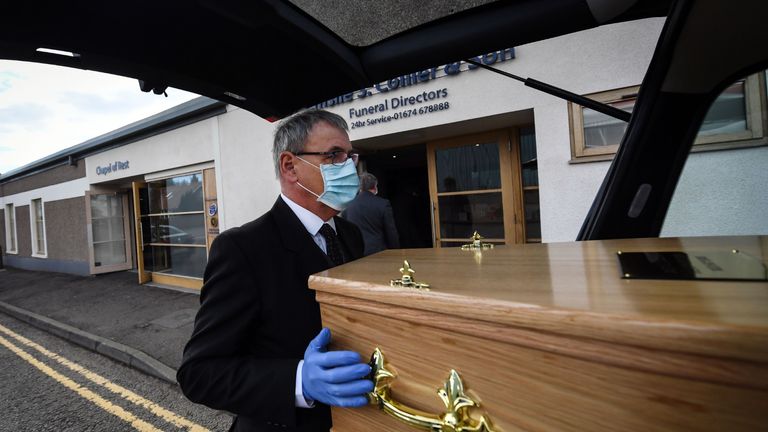 Funeral Director Emslie Collier wearing mask and gloves loads the coffin of care worker Janet Livingston, 60, who died of COVID-19, into the hearse at Emslie S. Collier and Son Funeral Directors in Montrose, east Scotland on May 4, 2020, to be driven to the crematorium for the funeral service. - Janet Livingston, a 60-year-old care worker, fell ill nearly three weeks ago after she returned home from a shift at a care home where three people had been infected with COVID-19. Despite initially testing negative for the virus she developed a high fever of 39 degrees and difficulty breathing. She died of COVID-19 in hospital with her 25-year-old son Jamie at her side. Jamie then had to go directly home to self-isolate for two weeks at his home in the coastal village called Ferryden in east Scotland, emerging to attend Janet's funeral on May 4, 2020. (Photo by Andy Buchanan / AFP) / AFP PHOTO ESSAY BY ANDY BUCHANAN (Photo by ANDY BUCHANAN/AFP via Getty Images)