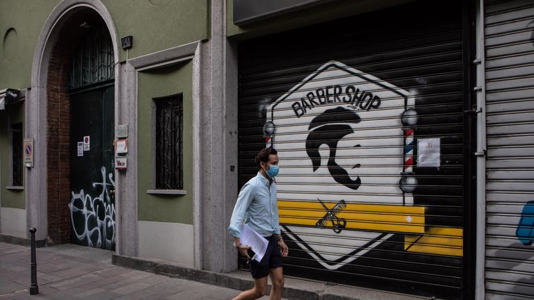 MILAN, ITALY - MAY 06: A man, wearing a protective face mask, walks past a shuttered barber shop on May 06, 2020 in Milan, Italy. Italy was the first country to impose a nationwide lockdown to stem the transmission of the Coronavirus (Covid-19), and its restaurants, theaters and many other businesses remain closed. (Photo by Emanuele Cremaschi/Getty Images)