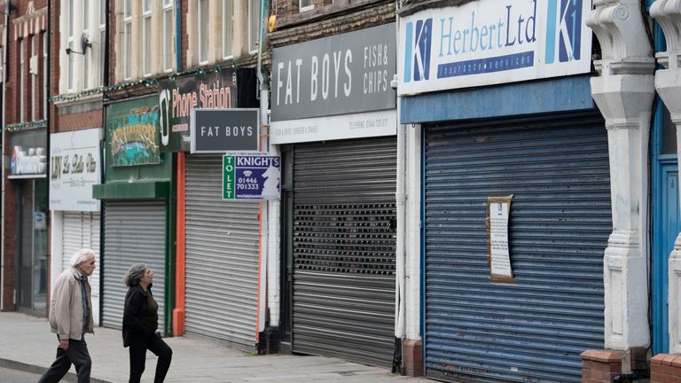 BARRY, UNITED KINGDOM - JUNE 12: A man and woman look at closed shops on during the coronavirus lockdown period on June 12, 2020 in Barry, United Kingdom. GDP fell by 20.4% in April, compared with the previous month, according to data from the Office for National Statistics. At the end of April the economy was about 25 per cent smaller than in February. The Welsh government has further relaxed COVID-19 lockdown measures this week, allowing people from different households to meet up outside while maintaining social distancing. Schools have remained closed and those who have been advised to shield at home can go outside again but have been told to avoid shopping. (Photo by Matthew Horwood/Getty Images)
