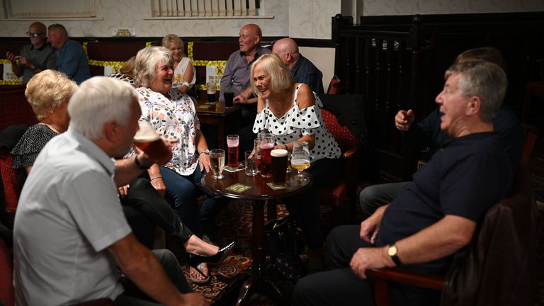 People enjoy a drink with yellow tape on the seats aiding social distancing inside the Burnley Miners Working Men's Social Club